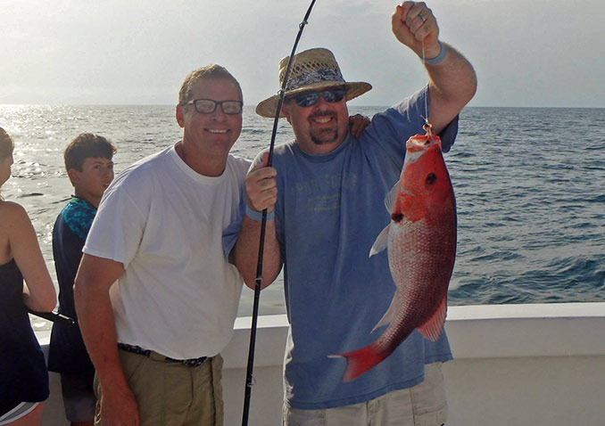 Capt Johnny Greene with a smiling father that has just caught him a Snapper